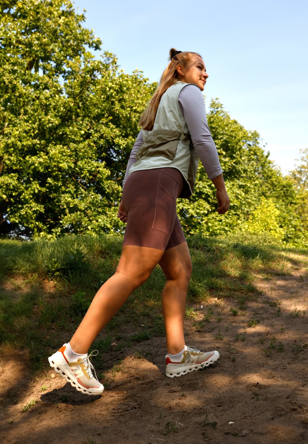 Lichte, beige wandelschoenen met grijze, oranje en gele accenten. Draag ze met bruine shorts en een lichtgroen vest over een langesleeve top.