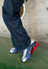 Tenisky Nike v bielo, námorníckom a červenom farebnom prevedení. Majú hladký syntetický zvršok, odpružené poduška v päte a textúrovanú podrážku.