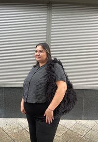 Sort-hvid stribet kortærmet bluse, sorte bukser og en stor, struktureret, fluffy sort taske med skulderrem.