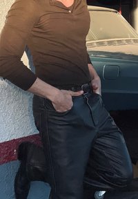 Fekete bőr nadrág, testhez álló fazonban, oldalsó zsebekkel, barna hosszúujjú inggel és fekete övvel párosítva, finom varrási részletekkel.