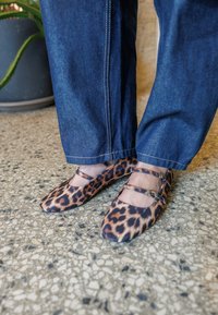 Leopardikuosisella kuosisella tasapohjaisilla kengillä, jotka ovat teräväkärkiset ja joissa on kapeat nilkkahihnat. Materiaali näyttää sileältä ja pehmeältä. Yhdistetty tummiin farkkuihin.
