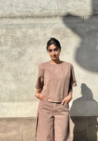 Jasnobrązowy strój lniany z krótkim rękawem i szerokimi spodniami. Prosty design i tekstura z przednimi kieszeniami i widocznymi szwami.