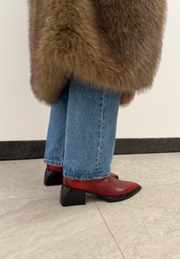 Κόκκινα μποτάκια αστραγάλου με μυτερή μύτη και μαύρο τετράγωνο τακούνι, σε συν δυασμό με ανοιχτό μπλε τζιν παντελόνι και καφέ ψεύτικη γούνα.