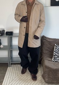 Tan houndstooth coat, brown button-up shirt, loose black trousers, brown gloves, and brown shoes. Soft textures, simple design, casual style.