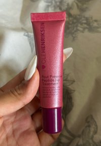 Pink metallic tube with a ribbed top, featuring black text. The bottom is a glossy dark purple. Product label: "Pout Preserve Peptide Lip Treatment."