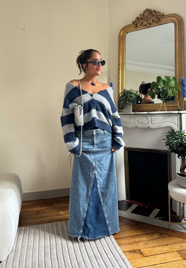 Oversized navy and grey striped knit sweater with an off-shoulder design, paired with a long denim skirt featuring a front split. Silver crossbody bag.