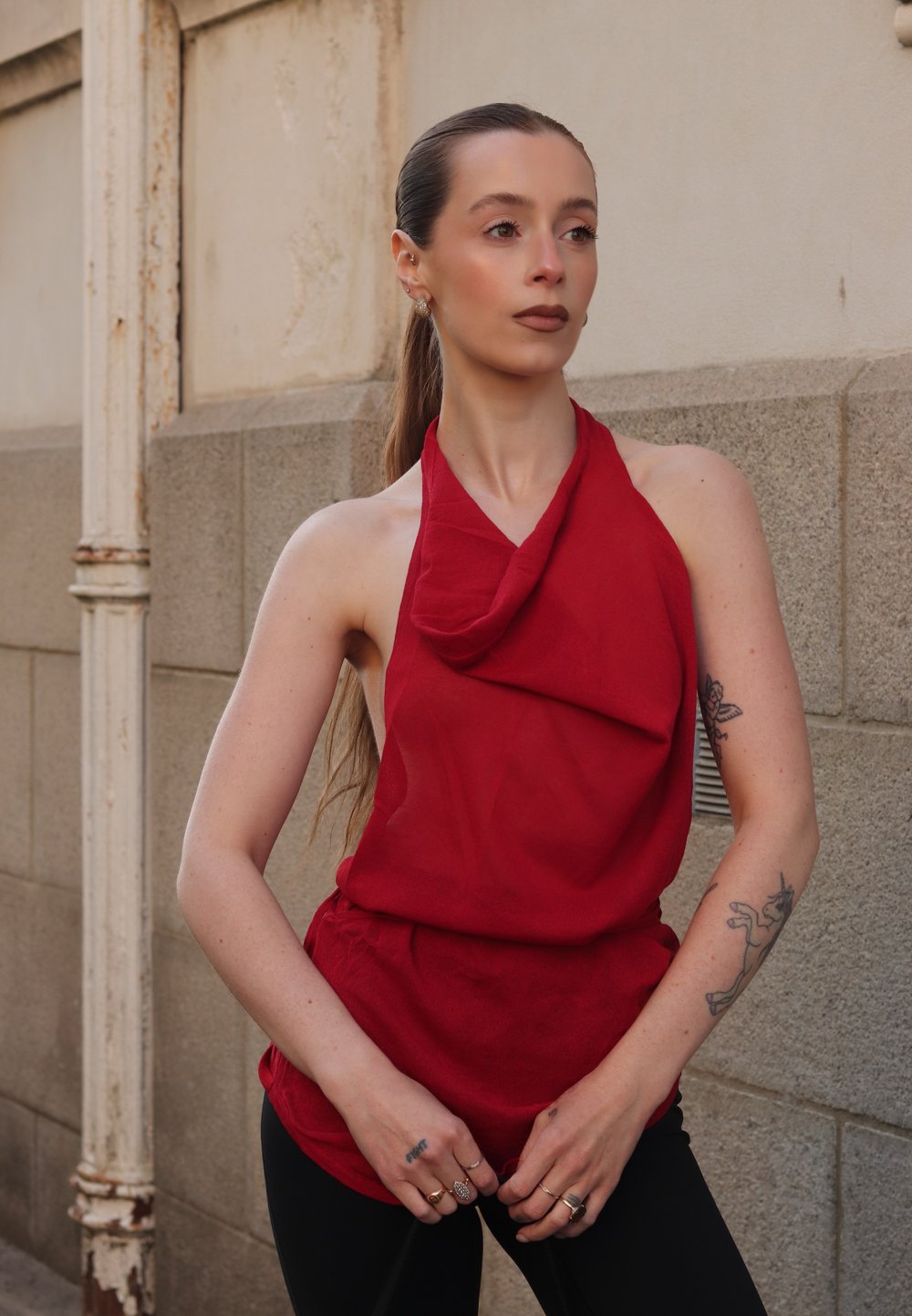 Rotes Oberteil im Halter-Stil, mit drapiertem Stoff, lockerem Schnitt und leichtem Material. Kombiniert mit schwarzen Hosen, die ein lässiges, aber dennoch markantes Design präsentieren.