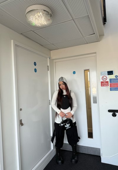 Conjunto en blanco y negro con un gorro de rayas, mangas largas, pantalones holgados y botas con plataforma, situado frente a una puerta interior sencilla.