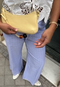 Gul læder clutch med frynser, lyseblå og hvide stribede vidde ben bukser, blomstret blondetop og hvide slip-on sko.