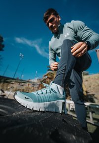 Chaussure de sport bleu clair avec tige en mesh texturé et semelle en caoutchouc blanche, avec un accent noir sur le talon et le système de laçage.