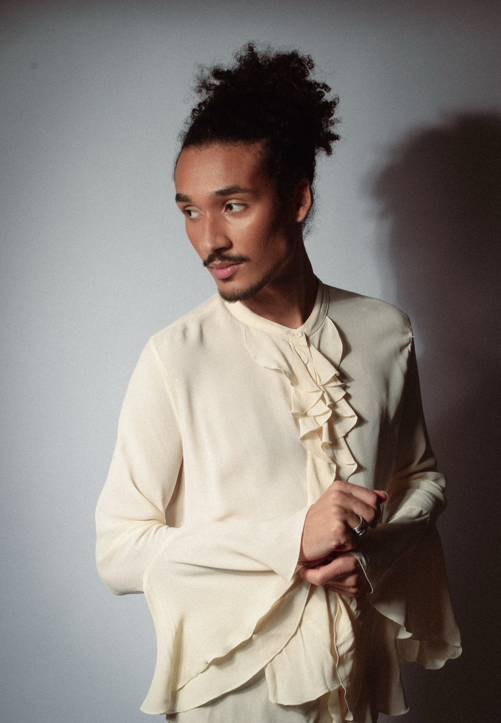 Blouse couleur crème avec des détails froncés sur le devant, des manches bell larges et un tissu doux et texturé. Design élégant et raffiné.