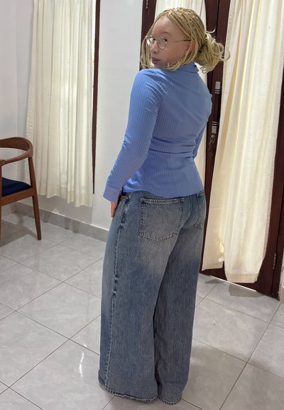 Top de manga larga de color azul claro con estructura acanalada y jeans de denim claro de estilo oversized. El conjunto tiene una cintura ajustada y un diseño de pierna acampanada.