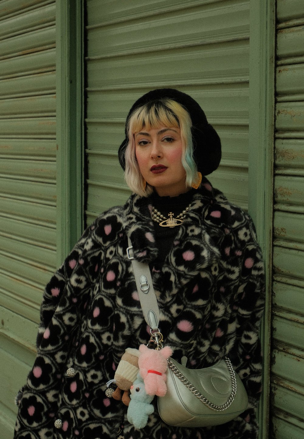 Svart faux fur-kåpe med rosa og svart leopardmønster, håndveske med sølvkjede, kosedyr-nøkkelringer, og en svart beret.