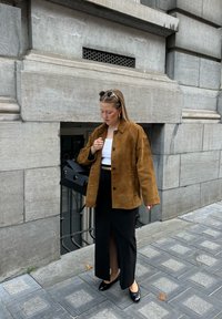 Pruun suède jope lõdva lõikega, must seelik eeslõhiku ja mustade lapitekkide, mustade tasaste kingade ja musta käekotiga. Kandsid päikeseprille ja kõrvarõngaid.