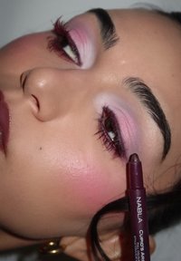 Bordeaux huulipuna pidetään lähellä kasvua, jossa on vaaleanpunaista luomiväriä, pitkät ripset ja poskipunatut posket; sileä ihotekstuuri; hienovarainen hehku.