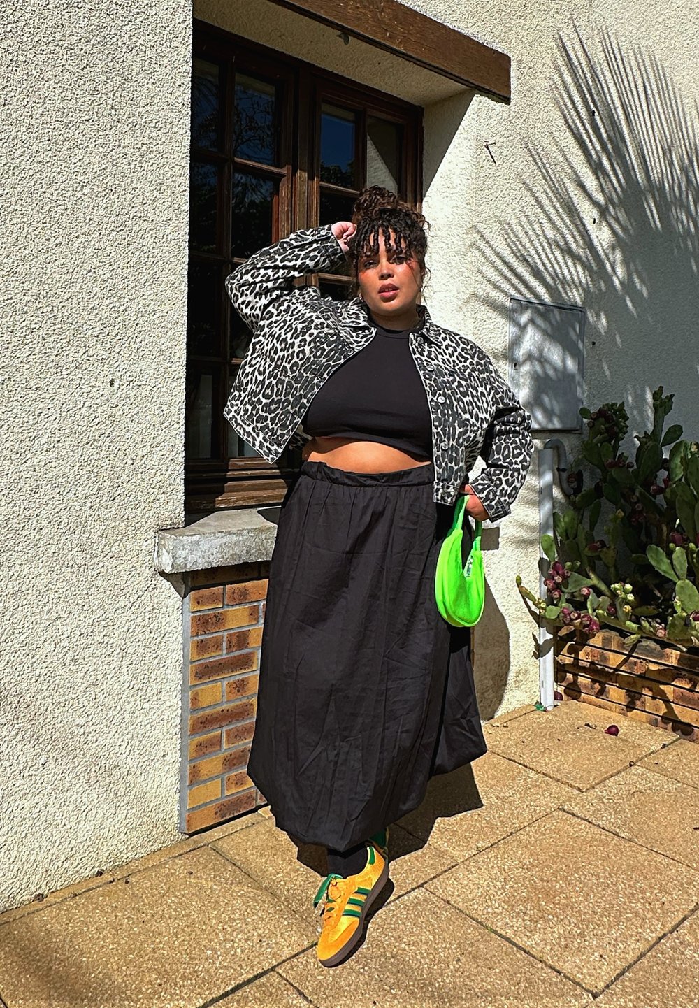 Leopardprint cropped jakke, sort crop top, sort maxi nederdel, lys grøn håndtaske, orange sneakers med grønne accenter; struktureret overflade.