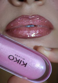 KIKO Milano Lipgloss in einem klaren, ovalen pinken Behälter; glänzender, glitzernder pinker Farbton auf den Lippen. Bemerkenswert für den Glanz und den Glittereffekt.