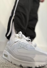 Weiße Sneaker aus strukturiertem Obermaterial, mit Schnürverschluss und sichtbarer Luftpolsterung. Verfügt über ein dezentes Logo und eine strapazierfähige Gummisohle.