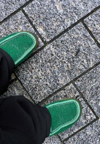 Zelene cipele od filca s debelim đonom i kontrastnim svijetlozelenim obrubom, smještene na teksturiranom sivom kamenolomu.