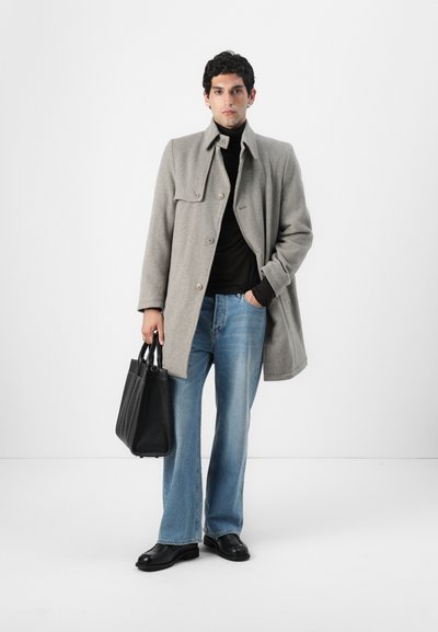 Abrigo de lana gris con cierre de botones, cuello de tortuga negro, jeans de campana azul claro y zapatos de cuero negros. Lleva un bolso tote de cuero negro.