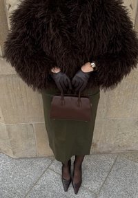 Bruine nepbontjas, groene kokerrok, zwarte leren handschoenen, een bruine handtas en puntige bruine hielen. Geweven en op maat gemaakte stijl.