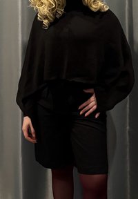 Haut noir court à manches longues, associé à un short noir. Le tissu semble doux, avec une coupe décontractée et sans motifs ni accents visibles.