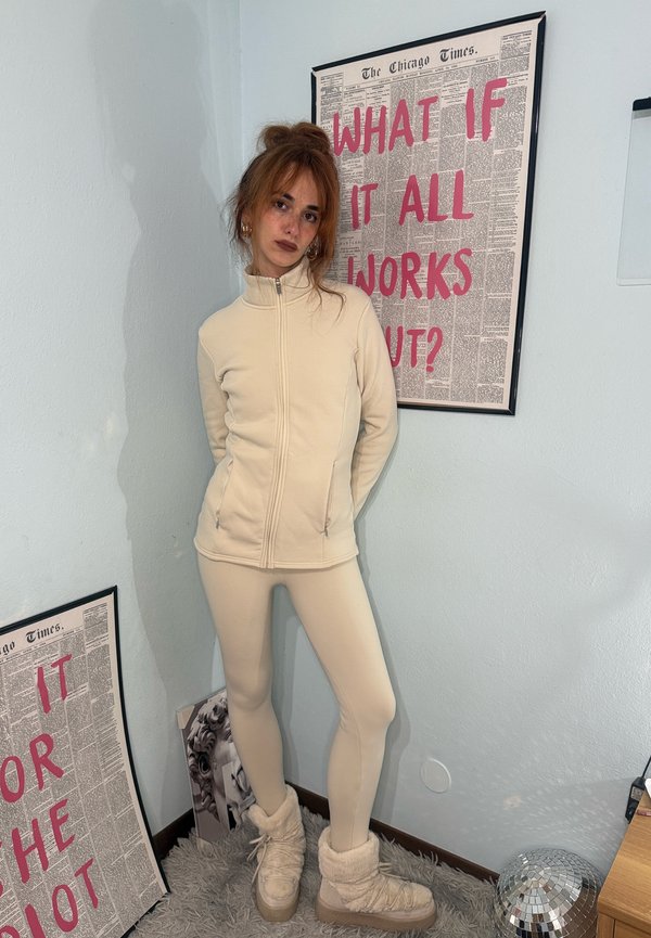 Beige Fleecejacke mit Reißverschluss und passende Leggings mit glatter Textur und figurbetontem Design. Ergänzt durch beige Stiefel mit Fellfutter.