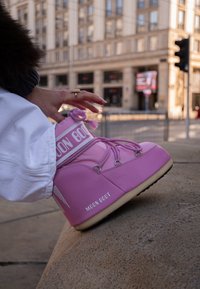 Roza Moon Boot s okruglim vrhom, bijelim detaljima i teksturiranim gumenim potplatom. Osigurana vezicama i remenom s logotipom.