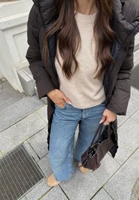 Pikk must puffer-jakk, beež lõngasviit, helesinised laiad teksad, pruunid kingad ja väike tume käsipakik. Juuksed on lahti.