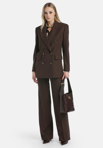Blazer marrón de doble botonadura con pantalones de pierna ancha a juego. Bolso de cuero texturizado en marrón oscuro con un sutil patrón de cocodrilo.