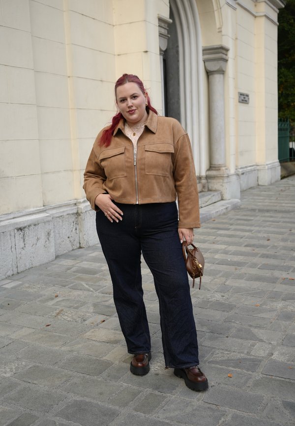 Brun nubuck croppet jakke med to frontlommer, mørkeblå vide bukser og brune platåsko. Liten brun veske med håndtak.
