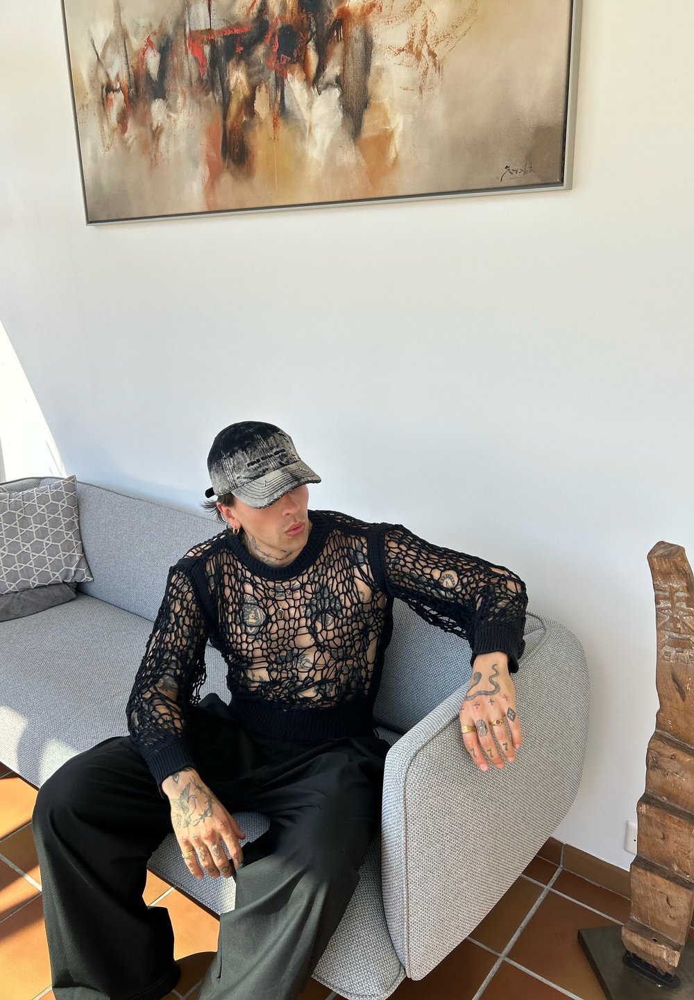 Svart stickad meshtröja med långa ärmar, med ett löst, öppet vävmönster. Kombinerad med svarta, lös passande byxor.