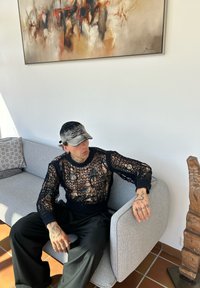 Svart stickad meshtröja med långa ärmar, med ett löst, öppet vävmönster. Kombinerad med svarta, lös passande byxor.