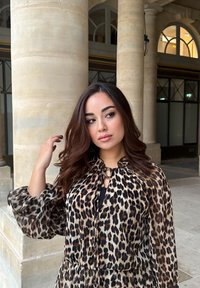 Μπλάζα με λεοπάρ σχέδιο και φουσκωτά μανίκια, κλείσιμο με κορδέλα στον λαιμό και ένα ελαφρύ, ρέον ύφασμα. Απαλή παλέτα χρωμάτων σε καφέ και μαύρο.