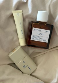 Korres kosmetiikan tuotteet: True Lip Shine, Natural Sheer Foundation sävyssä 95+ ja Lefko Eau De Toilette beige taustakankaalla.