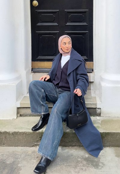 Abrigo casual navy sobre un suéter negro, jeans de cintura alta de corte amplio, botas de tobillo negras de punta cuadrada y un pequeño bolso negro. Hiyab rosa claro.