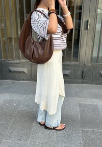 Brun faux læder hobo taske med et slasket design; stripet cropped top; lang, flydende hvid nederdel; lys blå brede bukser; flade sandaler.