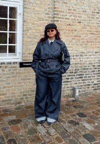 Denim trenchcoat med bred krage, belted midje og store lommer, kombinert med oversized denimbukser med oppbrettede cuffs.