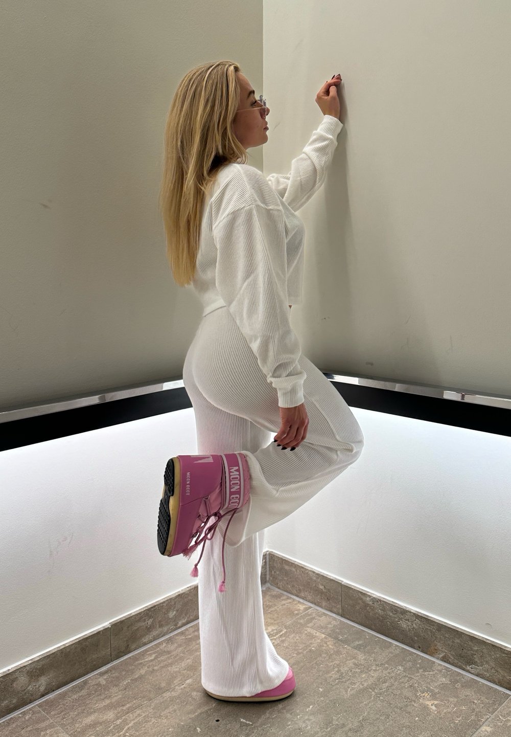 Λευκή ριμπ διπλή αντιαρματική φόρμα με μακριά μανίκια και φαρδιές παντελόνες, σε συνδυασμό με ροζ μπότες πλατφόρμας με κορδόνια που διαθέτουν επωνυμία "MOON GIRL".
