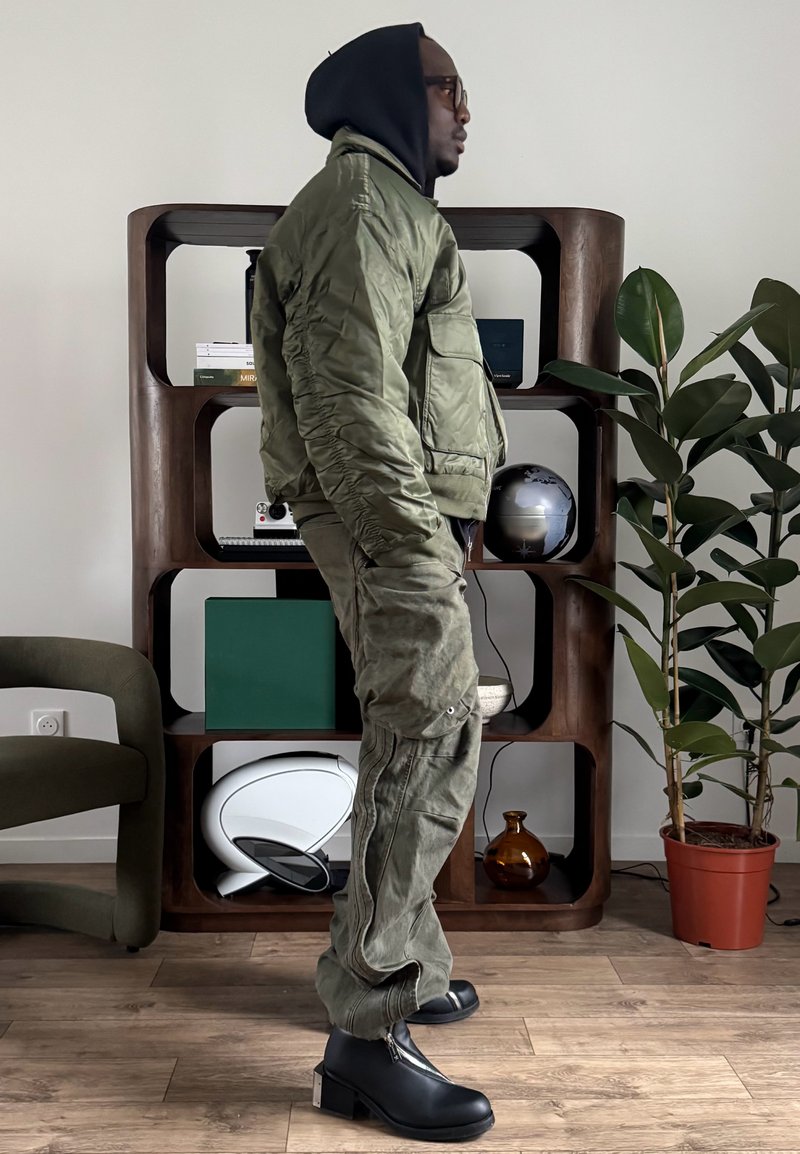 Veste bomber vert olive avec poignets côtelés et poches poitrine associée à un pantalon cargo ample. Bottines noires à fermeture éclair latérale et talon épais.