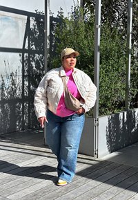 Lehkotkano ivorno jakno preko rožnatega majice, z modrimi džinsom in bež kapo za bejzbol. Bež torbica na čez in večbarvna obutev.