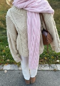 Överdimensionerad krämfärgad raggsocka med en rosa raggsocka, tillsammans med vita stickade byxor och ljusbruna ankelstövlar. Liten brun väska.