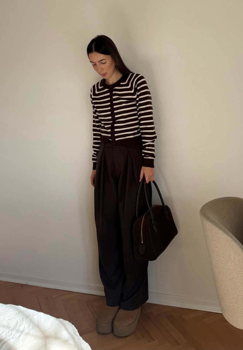 Striped brown and cream cardigan, high-waisted brown trousers, beige platform shoes, and a dark handbag. Simple, fitted design.