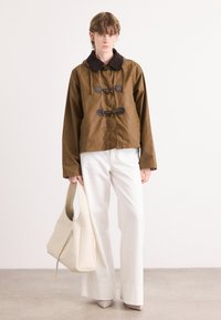Braune Übergangsjacke mit einem braunen Kragen und Knopfverschlüssen, kombiniert mit weißen weiten Hosen und einer beigen Tasche. Glatte Texturen durchgehend.