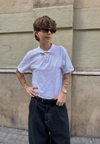 Valge lühikeste varrukatega polo särk, mustad kõrge vöökohaga laia säärega teksapüksid ja must vöö. Aksessuaaridena sõrmused ja käekell. Kandmisel tumedad päikeseprillid.