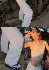 Baltas lina bikses ar vaļīgu piegriezumu, pelēks bezroku krekls un melnas slaidu sandales. Saules gaisma izgaismo auduma struktūru un ikdienišķo dizainu.