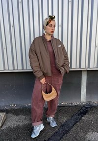 Καφέ αεροπλάνου μπουφάν, μπορντό κοστούμι από κοτλέ, γκρι αθλητικά παπούτσια και ταν τσάντα. Πατρόν μαντήλι στο κεφάλι και υπερμεγέθη σκουλαρίκια.