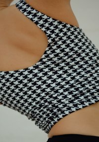 Maillot de bain à motif pied-de-poule noir et blanc avec un design élégant à découpe, doté d'un tissu texturé et d'une silhouette ajustée.