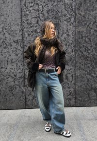 Μεγάλης διάστασης σκούρα καφέ ζακέτα, σχέδιο σκούρου φου scarve, εφαρμοστό καφέ πουκάμισο με σχέδιο ημισέλινο, φαρδύ μπλε τζιν και αθλητικά παπούτσια με σχέδιο.