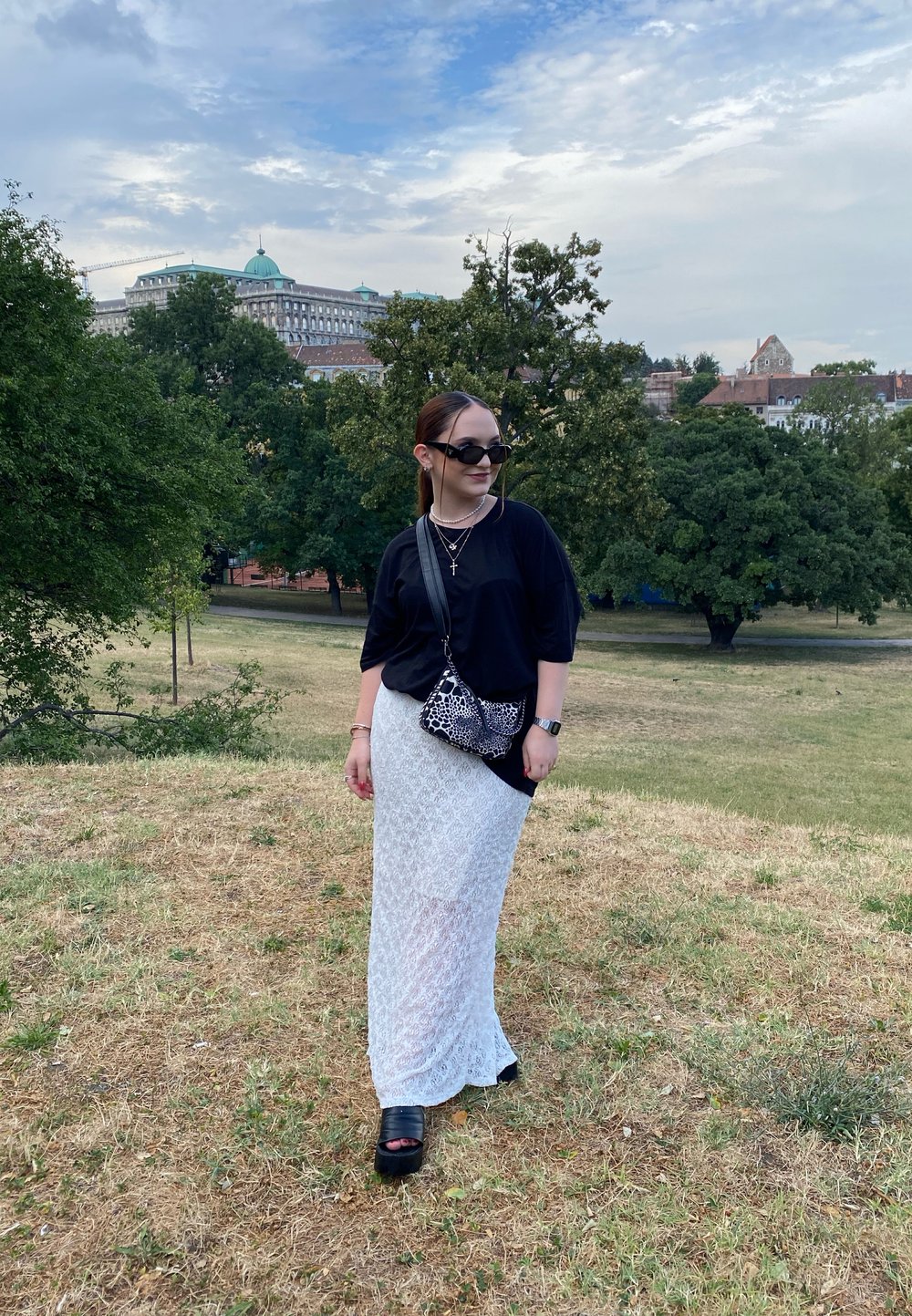 Sort løstsiddende top, hvid blonde maxiskirt, kraftige sorte platform-sko, sølv smykker og en sort-hvid mønstret taske. Grøn park baggrund.